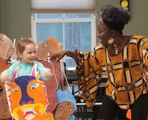 Mama Koku laughing with child holding dragon cutout