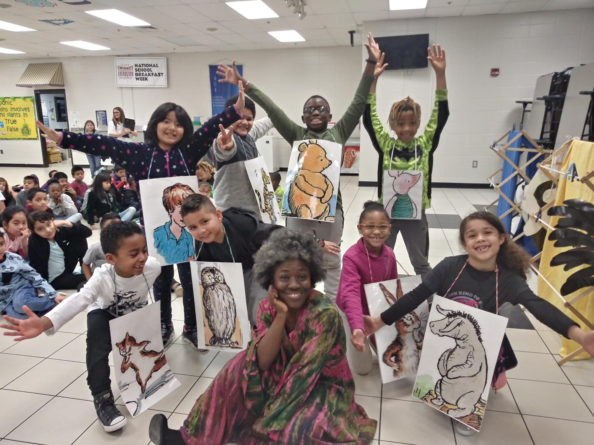 Children holding storybook character artwork with Mama Koku